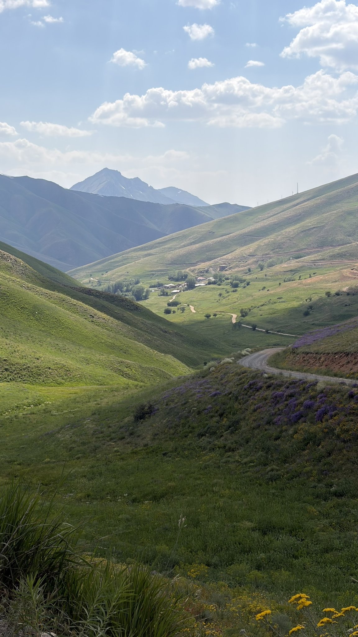 Serpentinenstraße durch ein grünes Hochtal in Ostanatolien mit Bergkulisse und einzelnem Dorf.