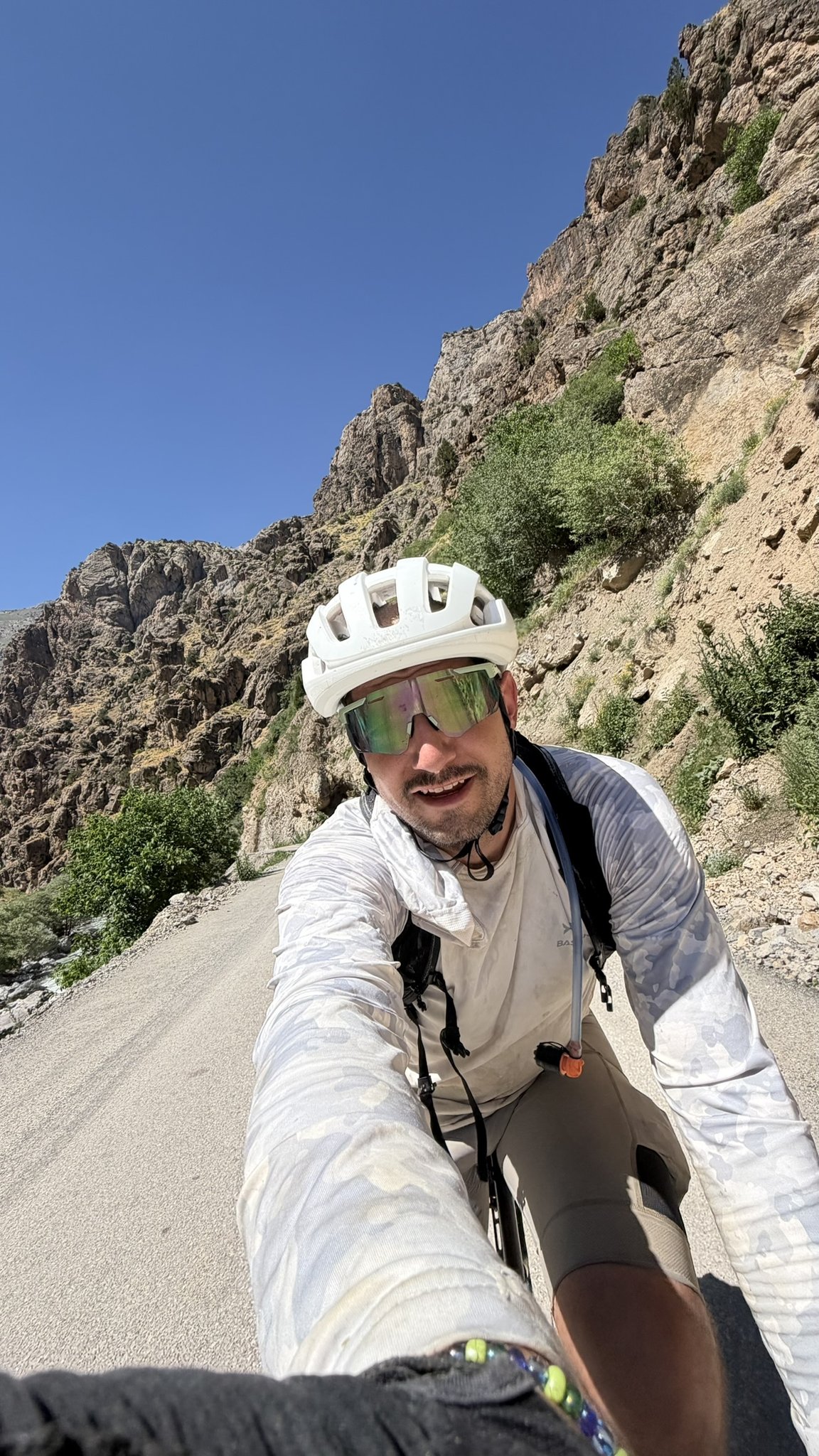 Selfie auf dem Rad in einer engen Felsschlucht bei greller Sonne, Fahrer in weißer Sonnenschutzkleidung.